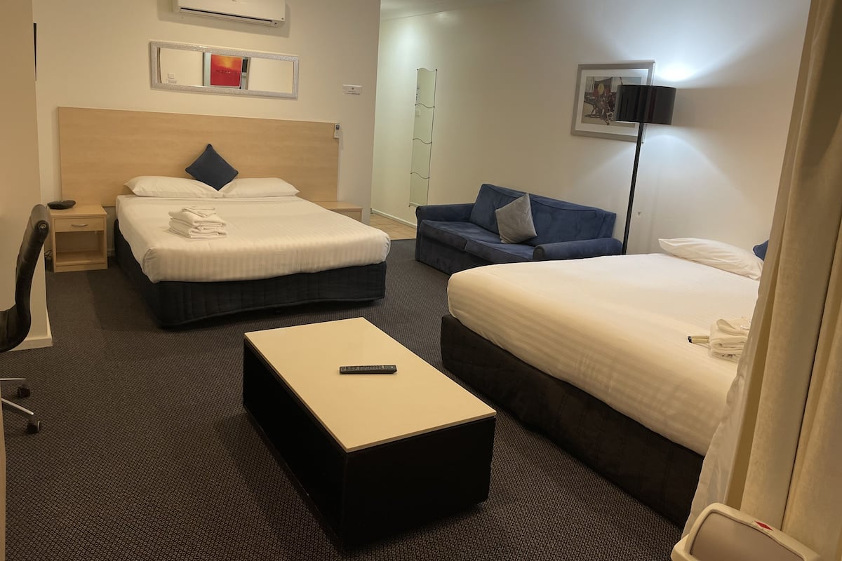 A hotel room with two beds, a sofa, a desk, and a chair.