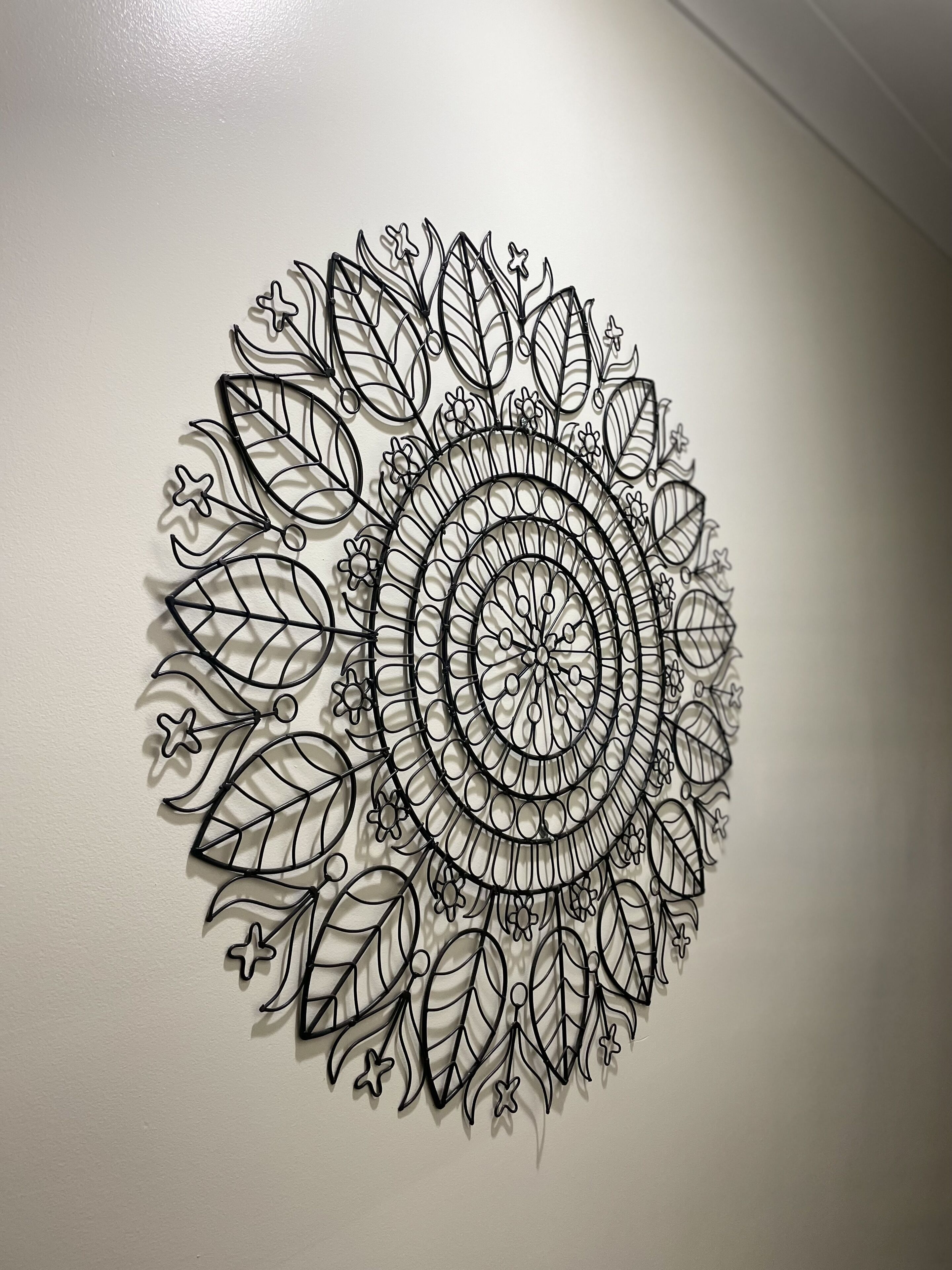 Una obra de arte mural con un diseño circular de mandala que presenta hojas y flores.
