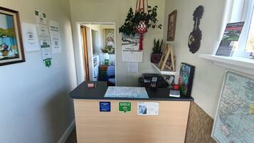 A reception desk with a calendar, a map, and a sign about Cornwall Park.