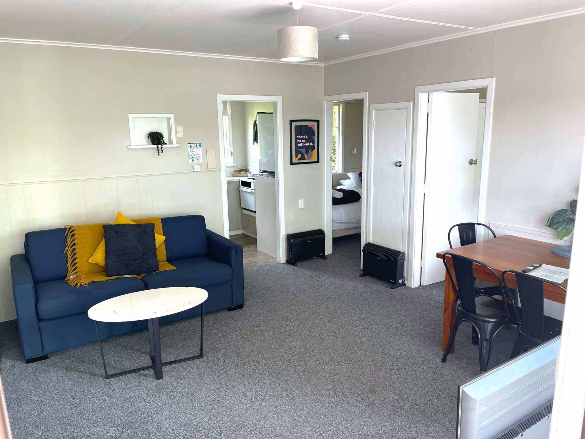 A compact living space with a sofa, a small table, a kitchenette, and a dining area.