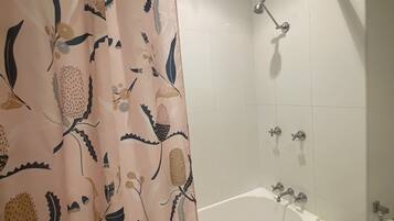 A bathroom with a bathtub, shower, and a curtain with a floral pattern.