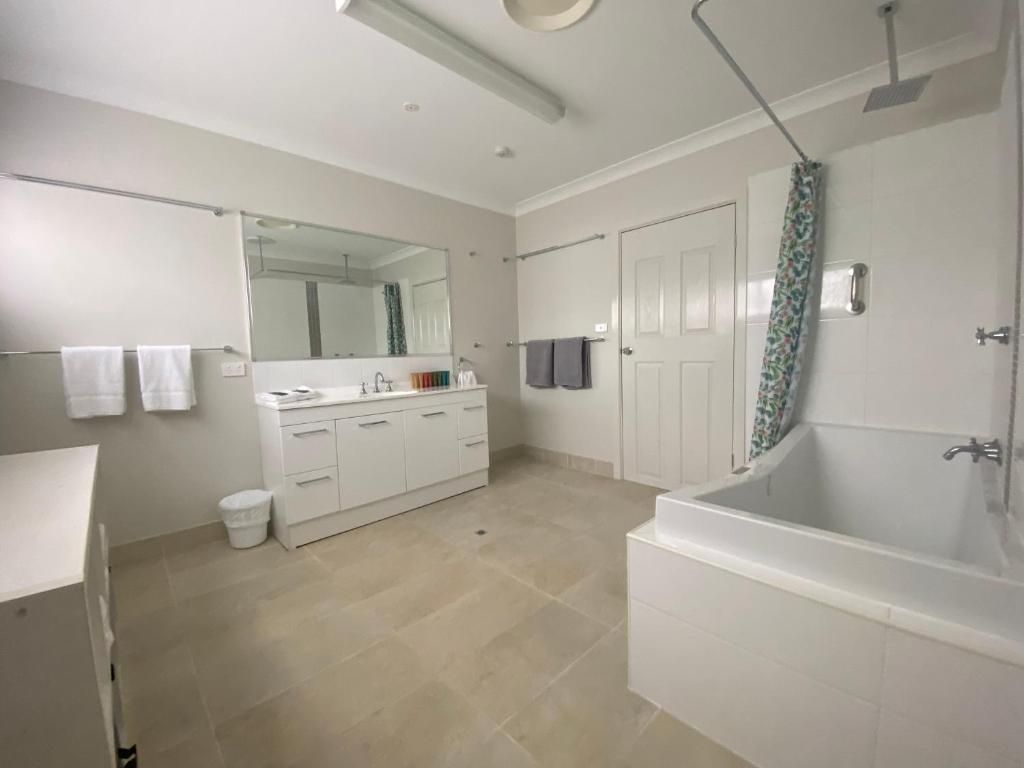 Un baño moderno con una bañera, un espejo grande y un inodoro.