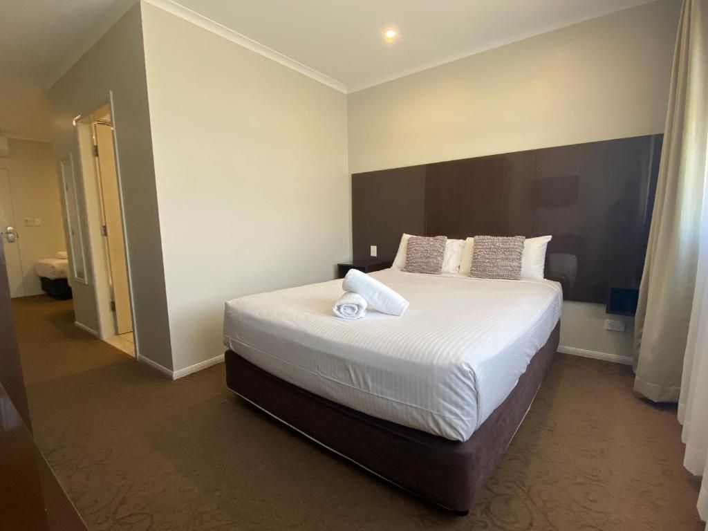 Quarto de hotel com uma cama grande, cabeceira escura e piso coberto por carpete.