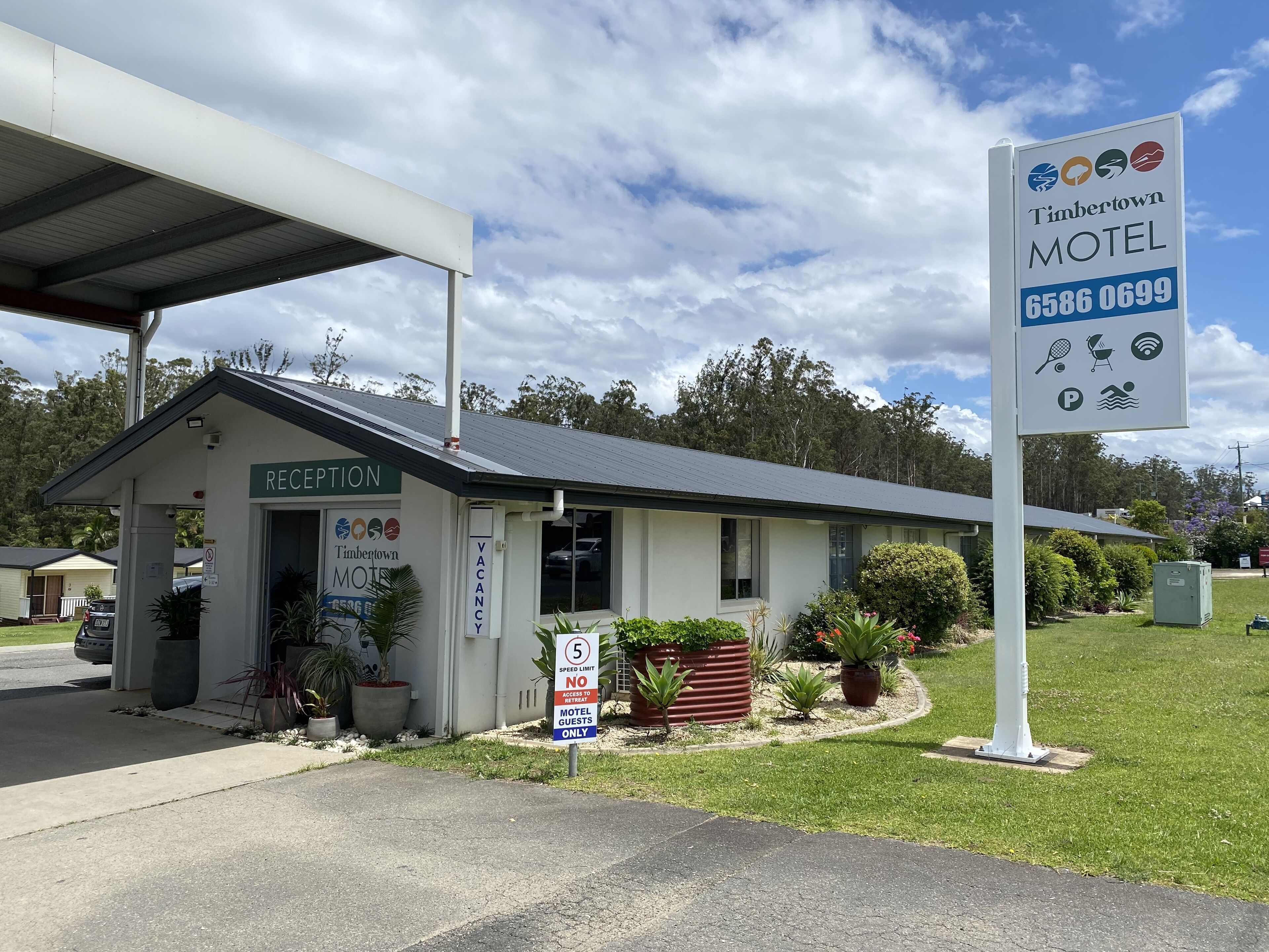 A small, single-story motel with a reception desk, a speed limit sign, and a sign indicating it is for motel guests only.