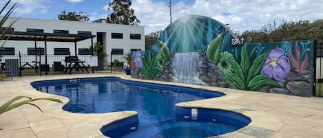 Una piscina al aire libre, sillones reclinables de piscina