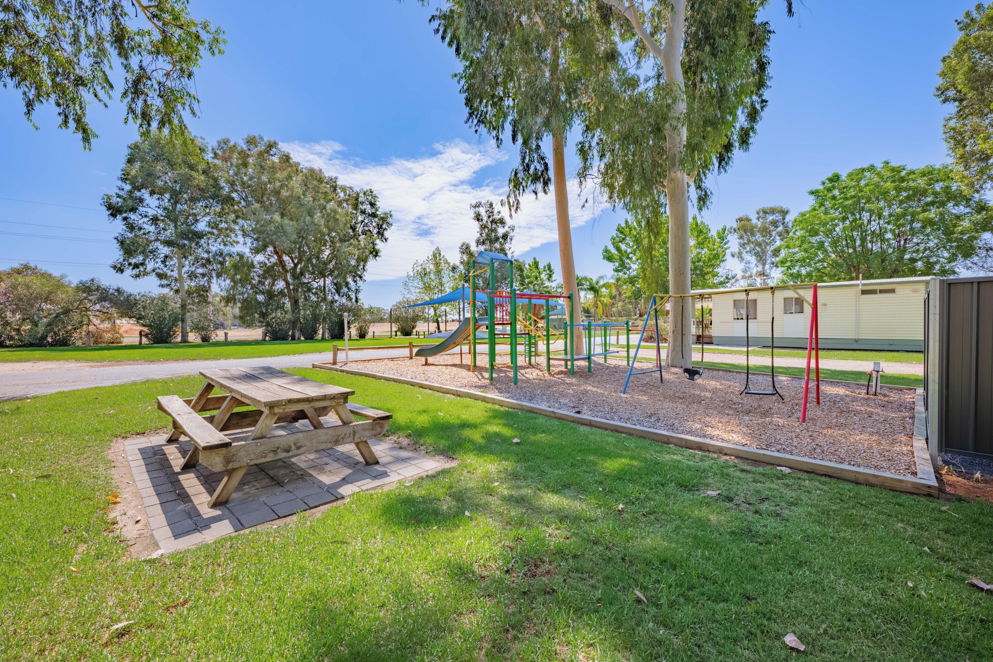 A playground with a picnic table, swings, and climbing structures.