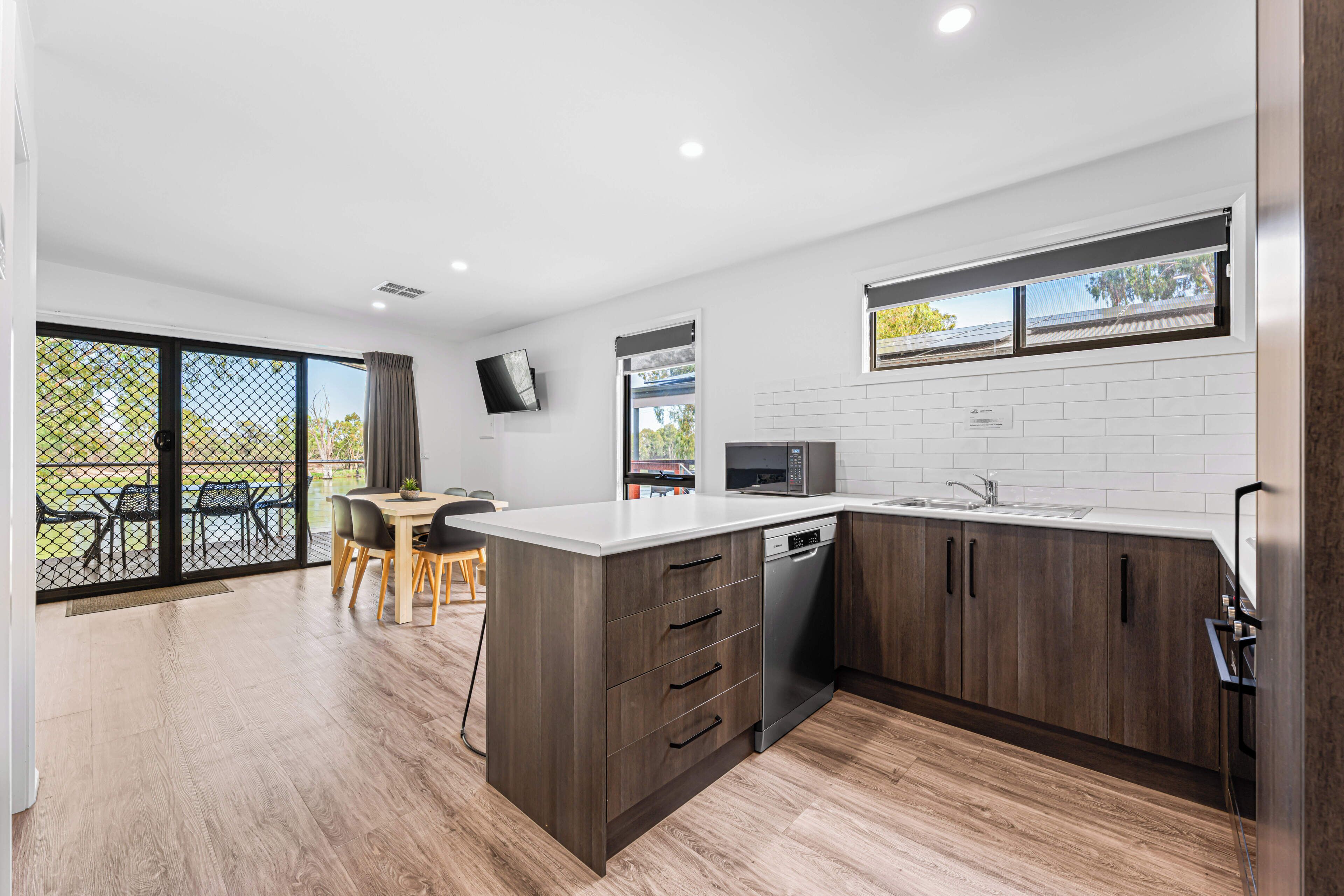A modern kitchen with a large island, built-in appliances, and a dining area with a view.
