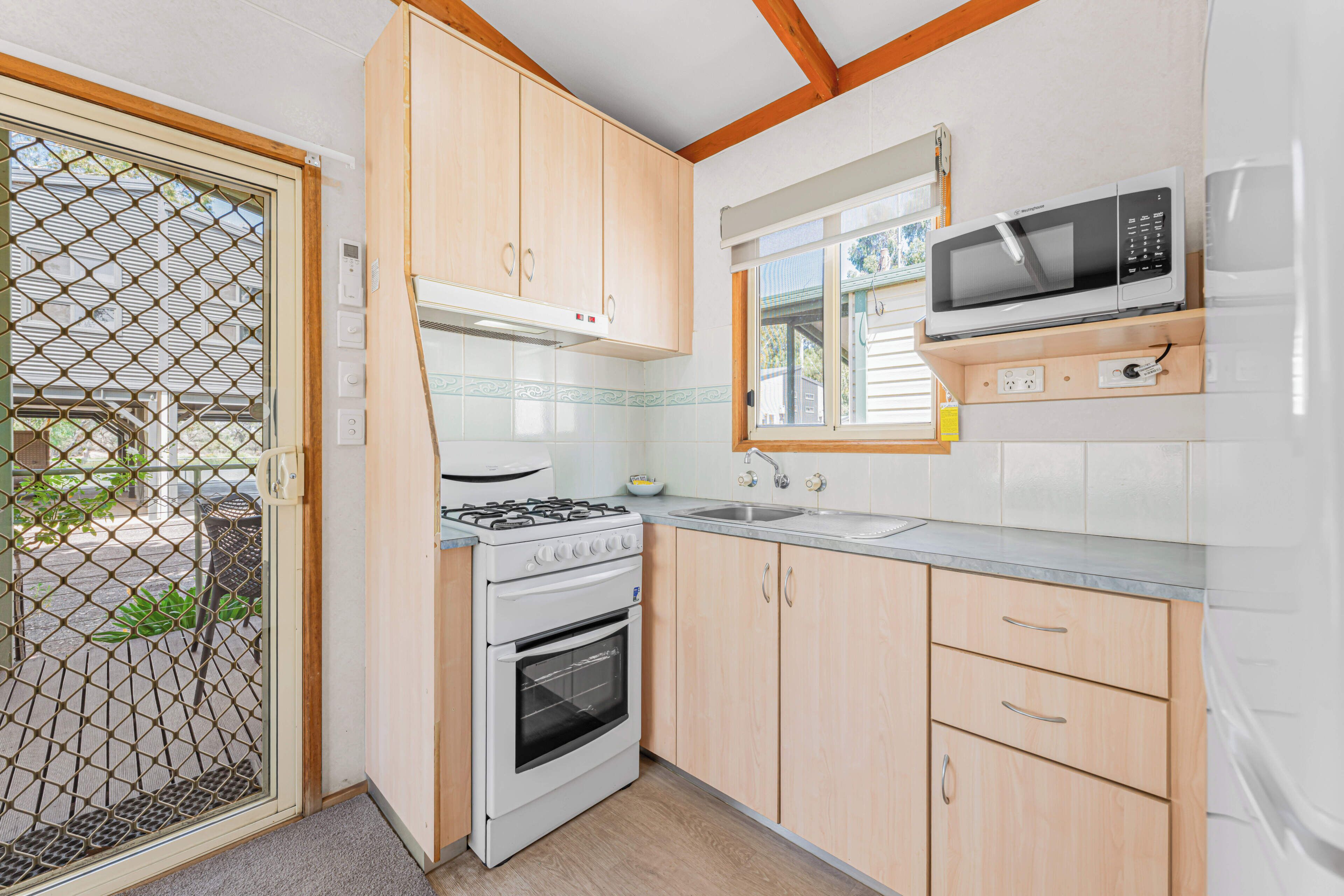 A compact kitchen with a gas stove, oven, microwave, and wooden cabinets.