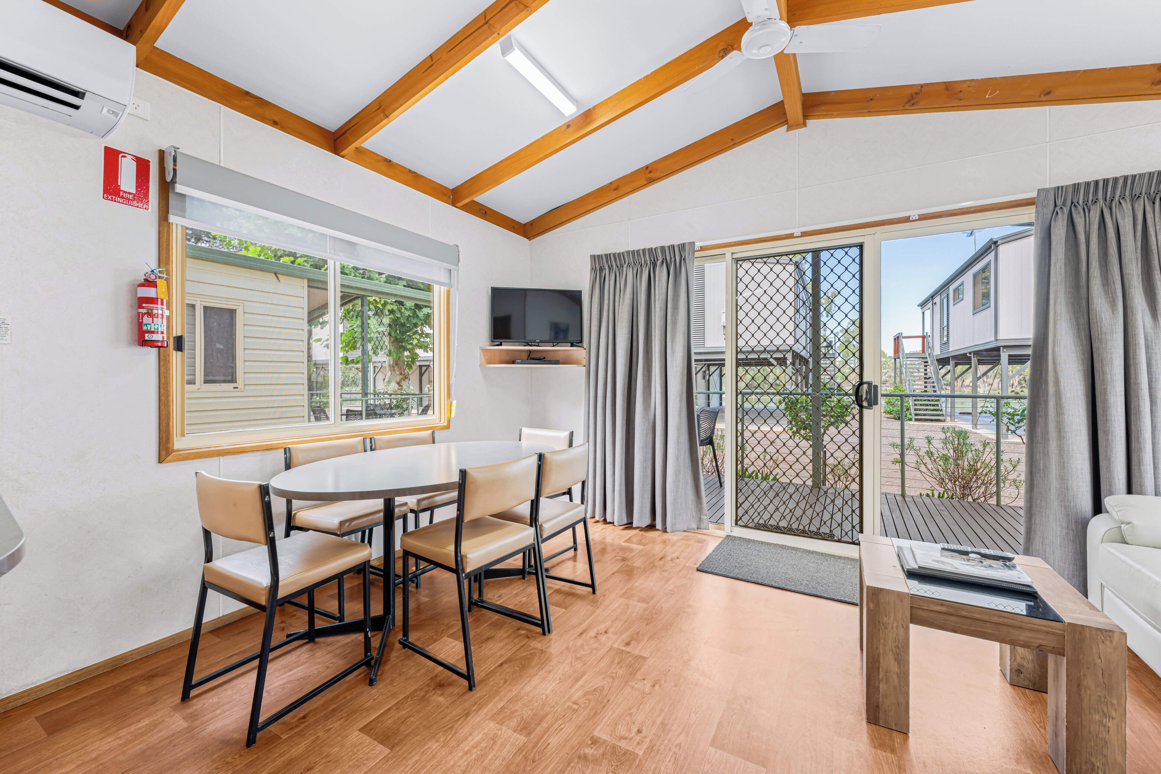 A room with a dining table, chairs, a TV, and a sofa.