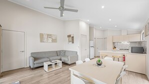 Una cocina moderna con armarios blancos, un microondas y una zona de comedor con mesa y sillas.
