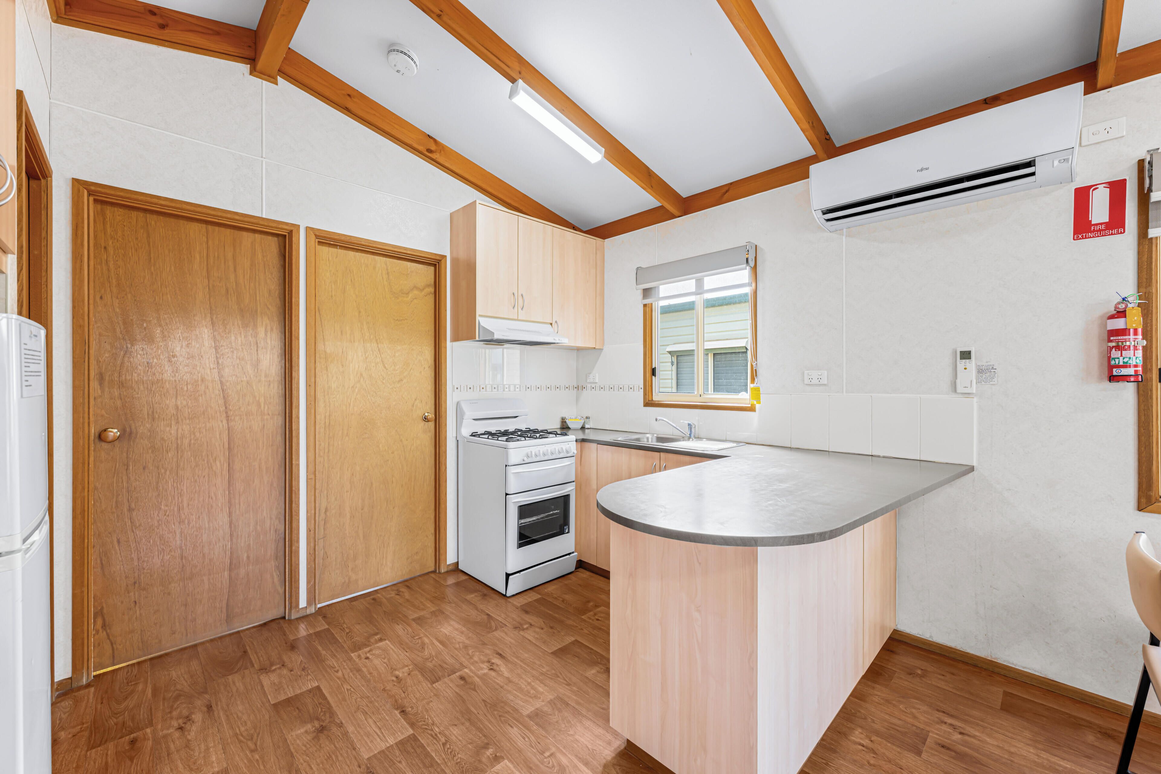 A modern kitchen with wooden cabinets, a built-in stove, and a large island.