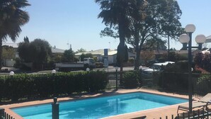 Una piscina con área vallada, sillas de descanso y un letrero que indica que los niños deben ser supervisados por un adulto en todo momento.