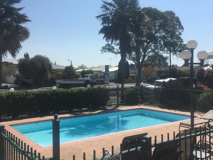 A swimming pool with a fenced area, lounge chairs, and a sign indicating children must be supervised by an adult at all times.