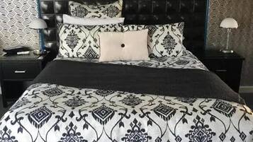 Een bed met een gebedruid sprei, twee nachtkastjes met lampen en een donker hoofdbord.