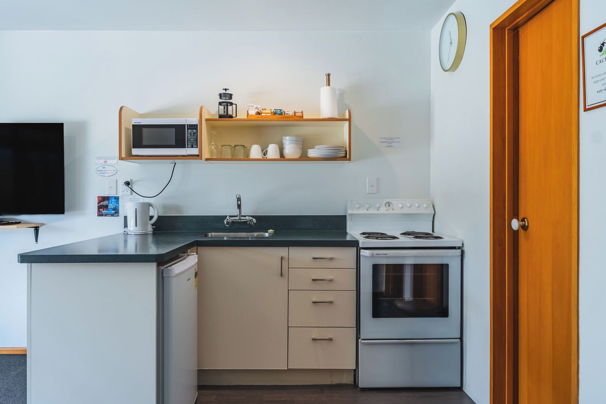 A compact kitchen with a microwave, stove, sink, and a small refrigerator.