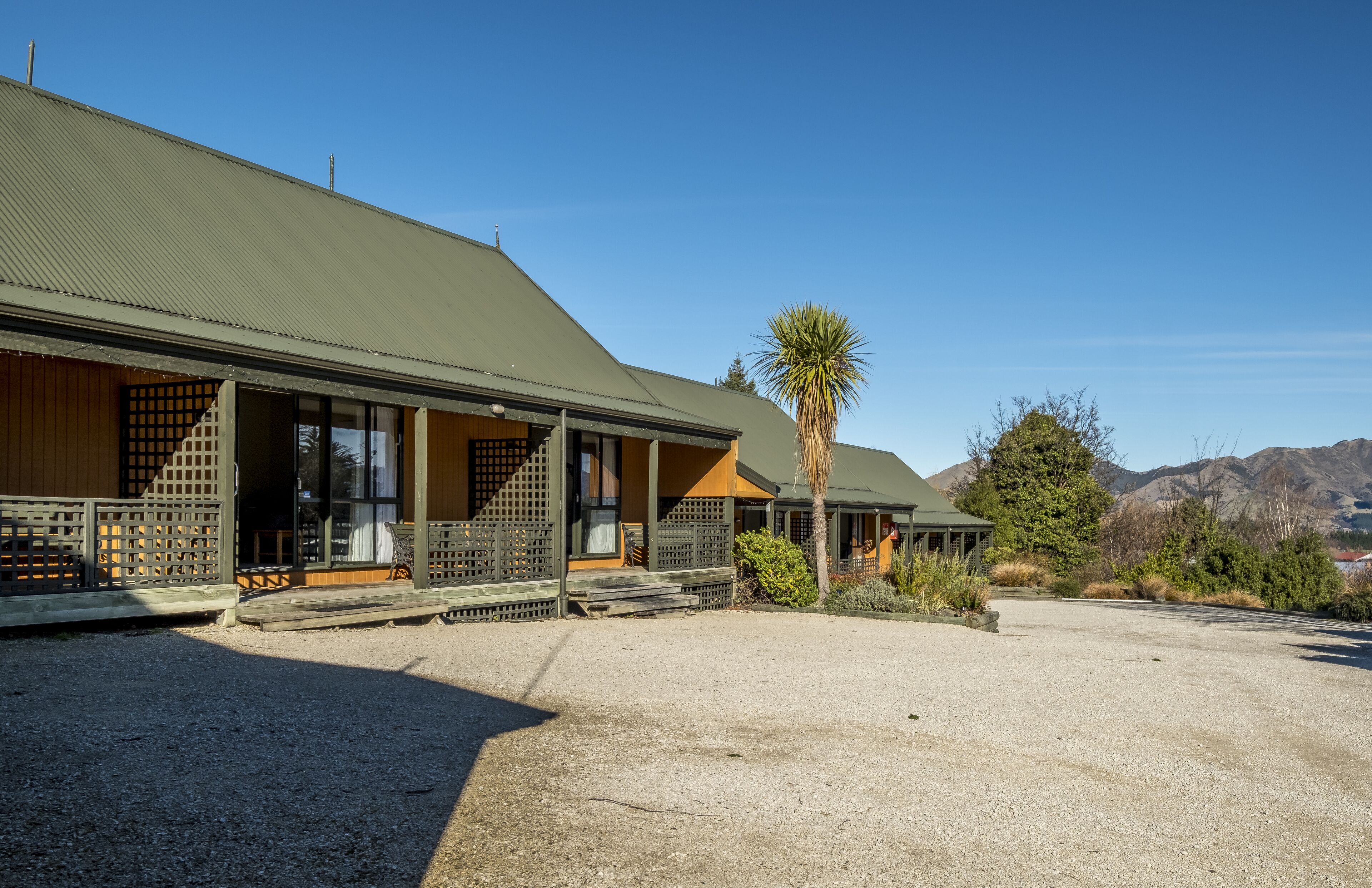 A building with a green roof, wooden exterior, and a covered porch with lattice railings.