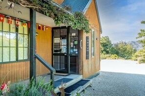 A wooden building with a reception desk, a sign indicating a reception area, and a view of a mountain in the background. - Alpine Garden Motel (Hanmer Springs)