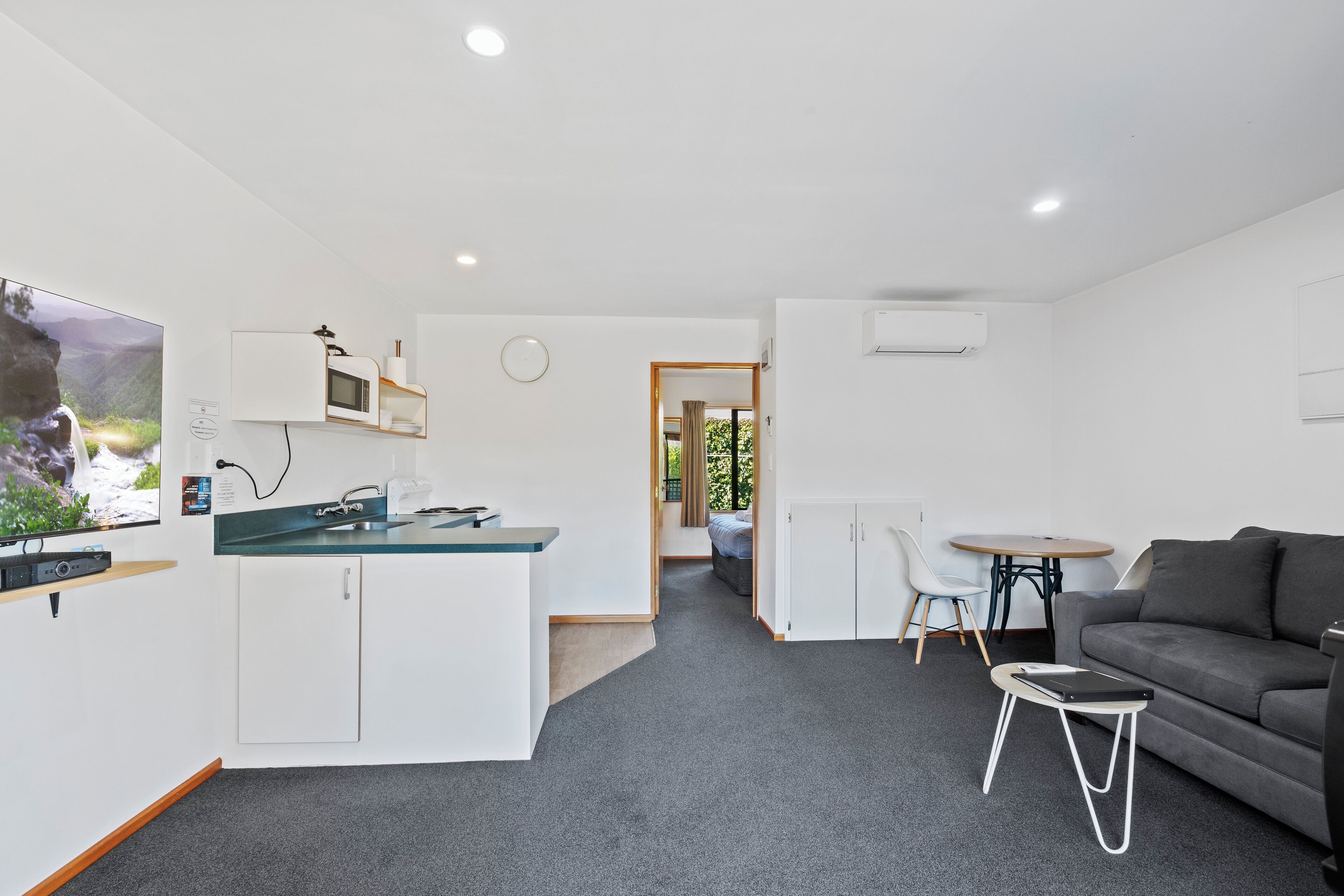 Un espace de vie moderne et compact comprenant un coin cuisine, un canapé, un coin repas et une petite table.