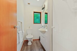 A small bathroom with a toilet, sink, and mirror. - Alpine Garden Motel (Hanmer Springs)