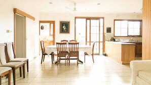 Una cocina amplia con comedor, muebles de madera y un gran ventanal que deja entrar luz natural.