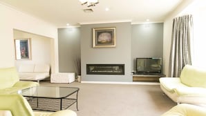 Una sala de estar con chimenea, dos sofás, una mesa de centro y un televisor.