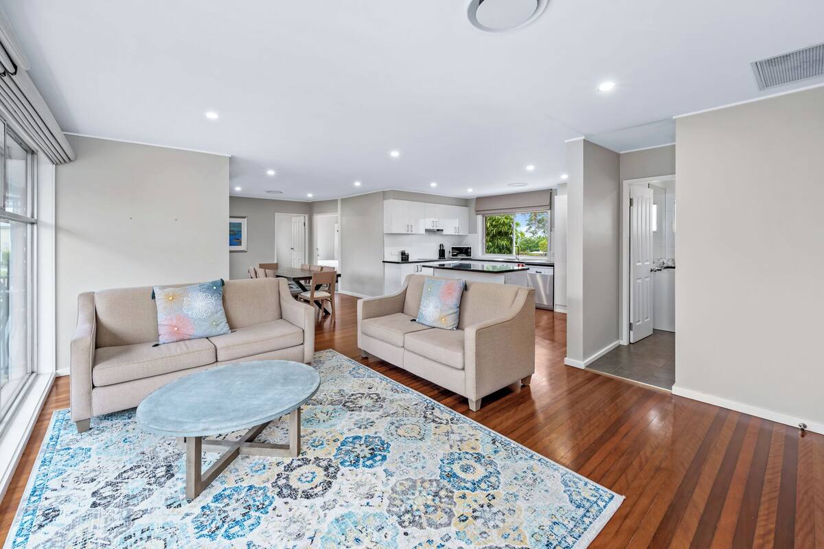A modern living room with two sofas, a coffee table, and a patterned rug.