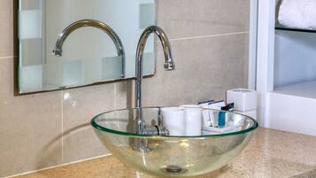 A modern bathroom with a glass bowl sink, a chrome faucet, and a mirror above it.