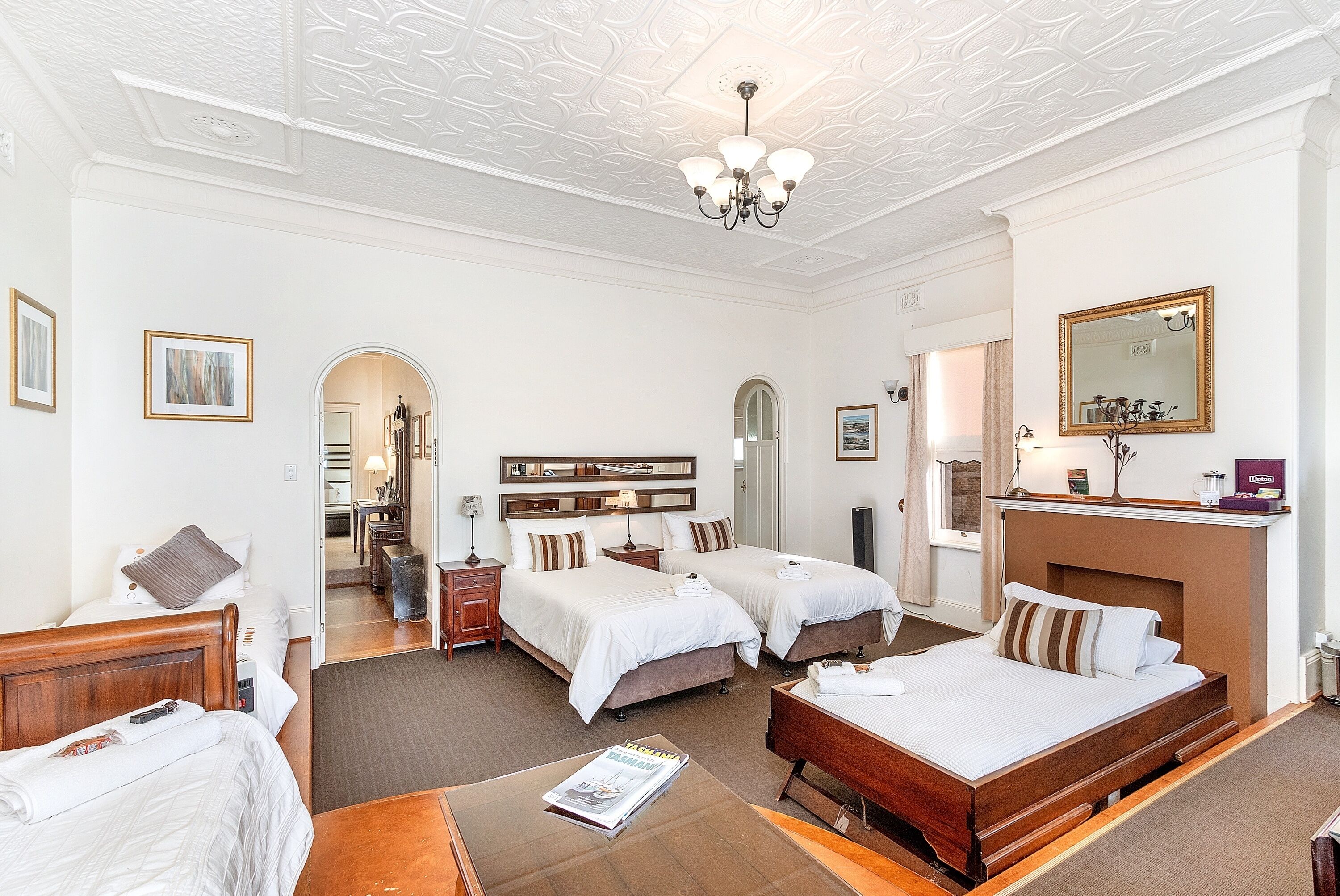 A hotel room with two beds, a wooden headboard, a mirror, and a small table with a magazine.