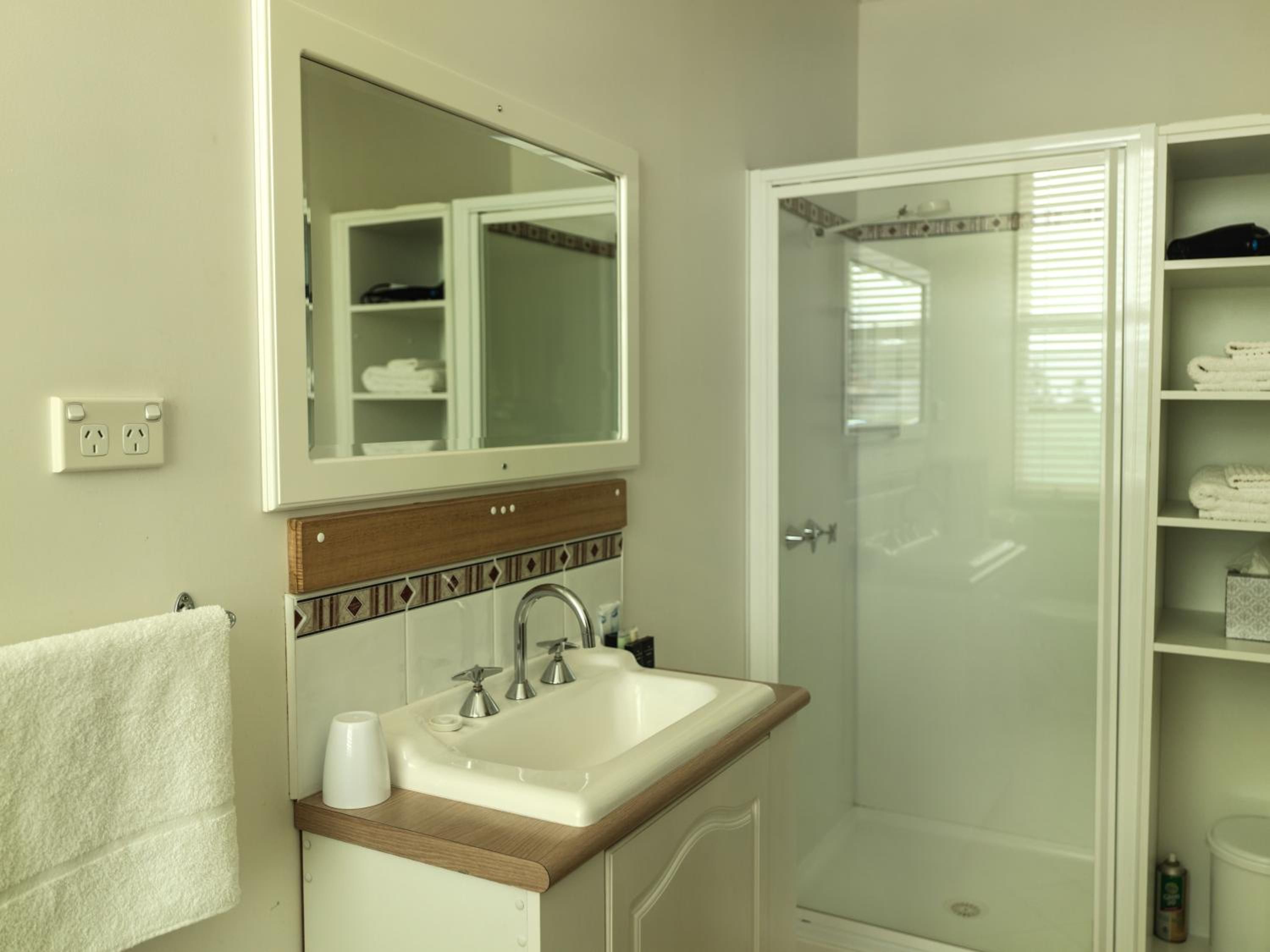 Une salle de bain avec un lavabo, un miroir et une douche.