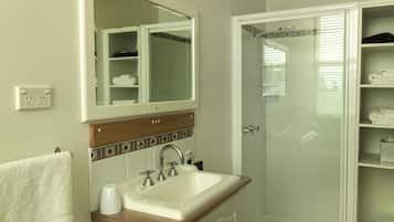 A bathroom with a sink, mirror, and shower.