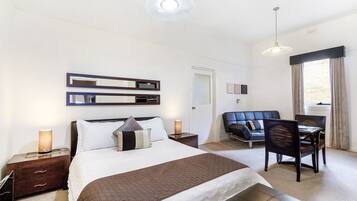 A hotel room with a bed, bedside tables, a desk, and a chair.