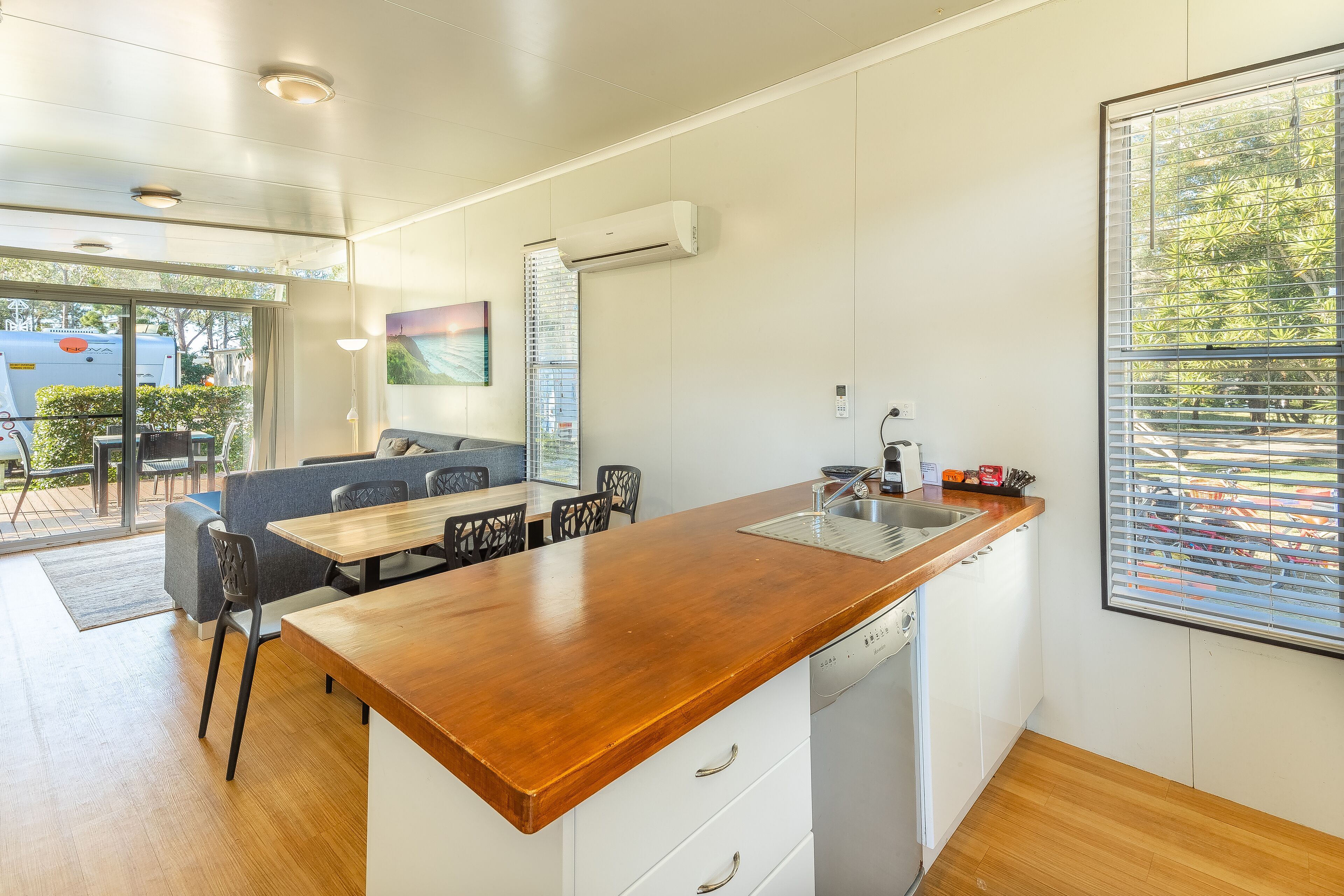 A modern kitchen with a wooden countertop, white cabinets, and a built-in dishwasher.