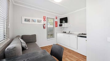 Un espacio habitable compacto con sofá, mesa de comedor, área de cocina con microondas y extintor.