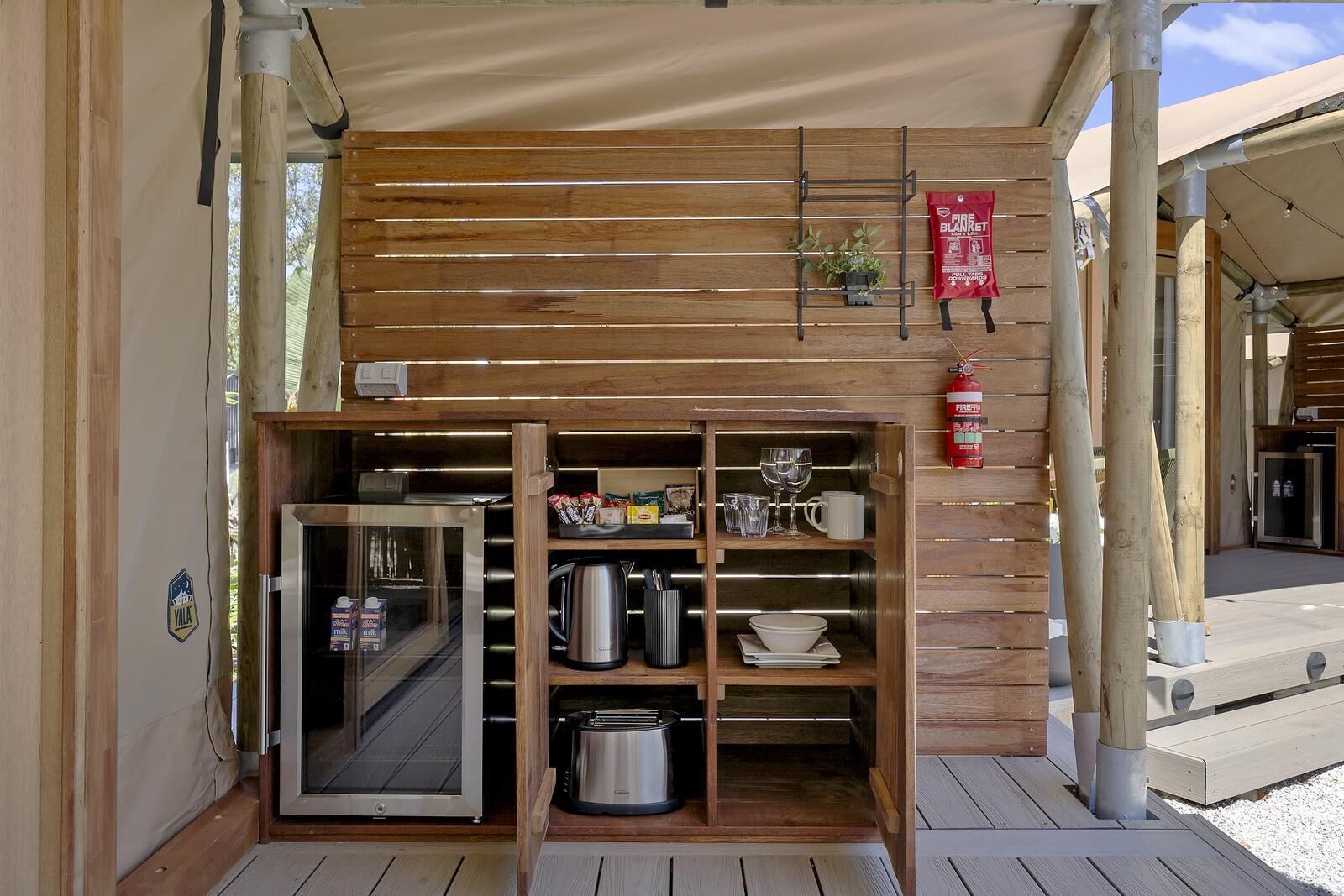 A compact kitchenette with a refrigerator, stove, and various kitchen utensils.