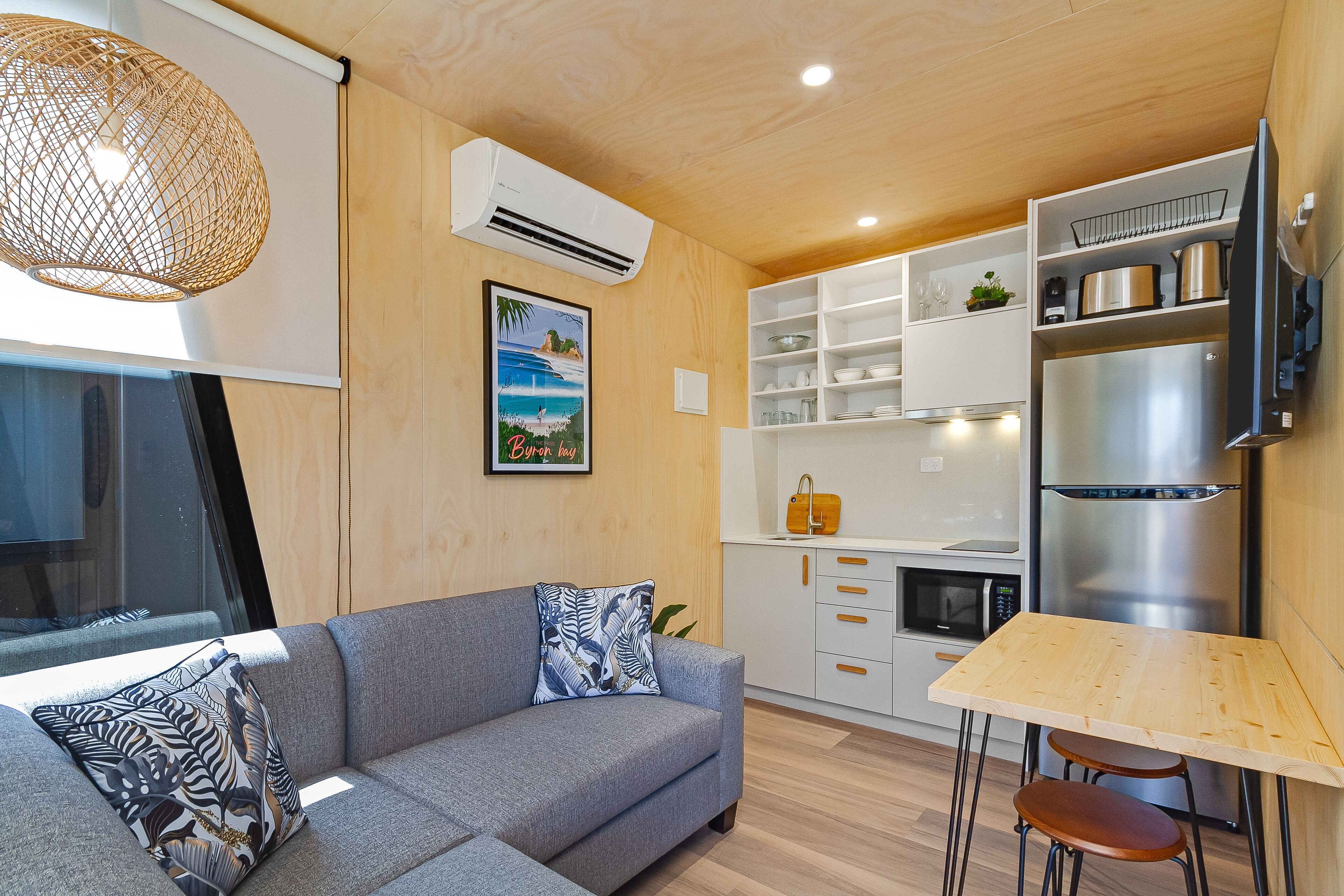 Una cocina moderna con sofá gris, mesa de madera y armarios empotrados.