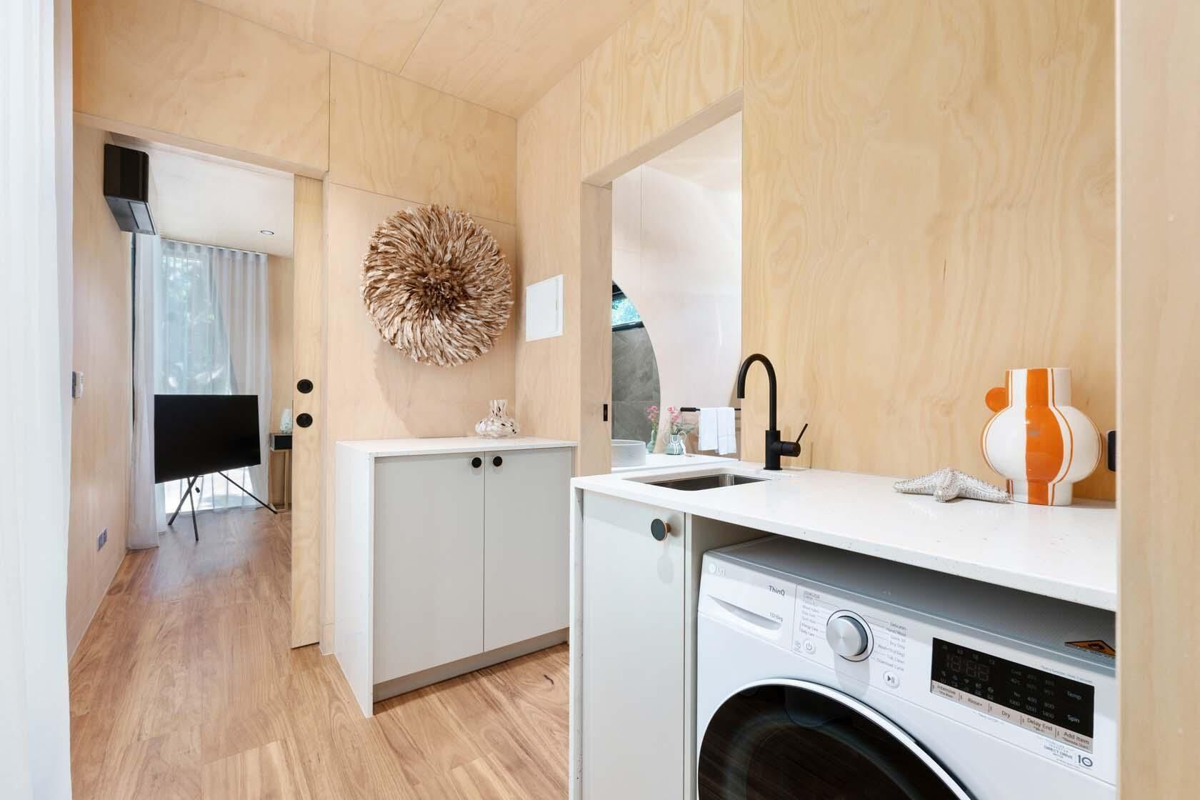Una cocina compacta con lavadora, un lavabo y un armario.