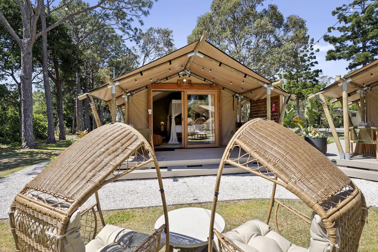 A bungalow with a covered porch, wicker furniture, and a view of the surrounding forest.