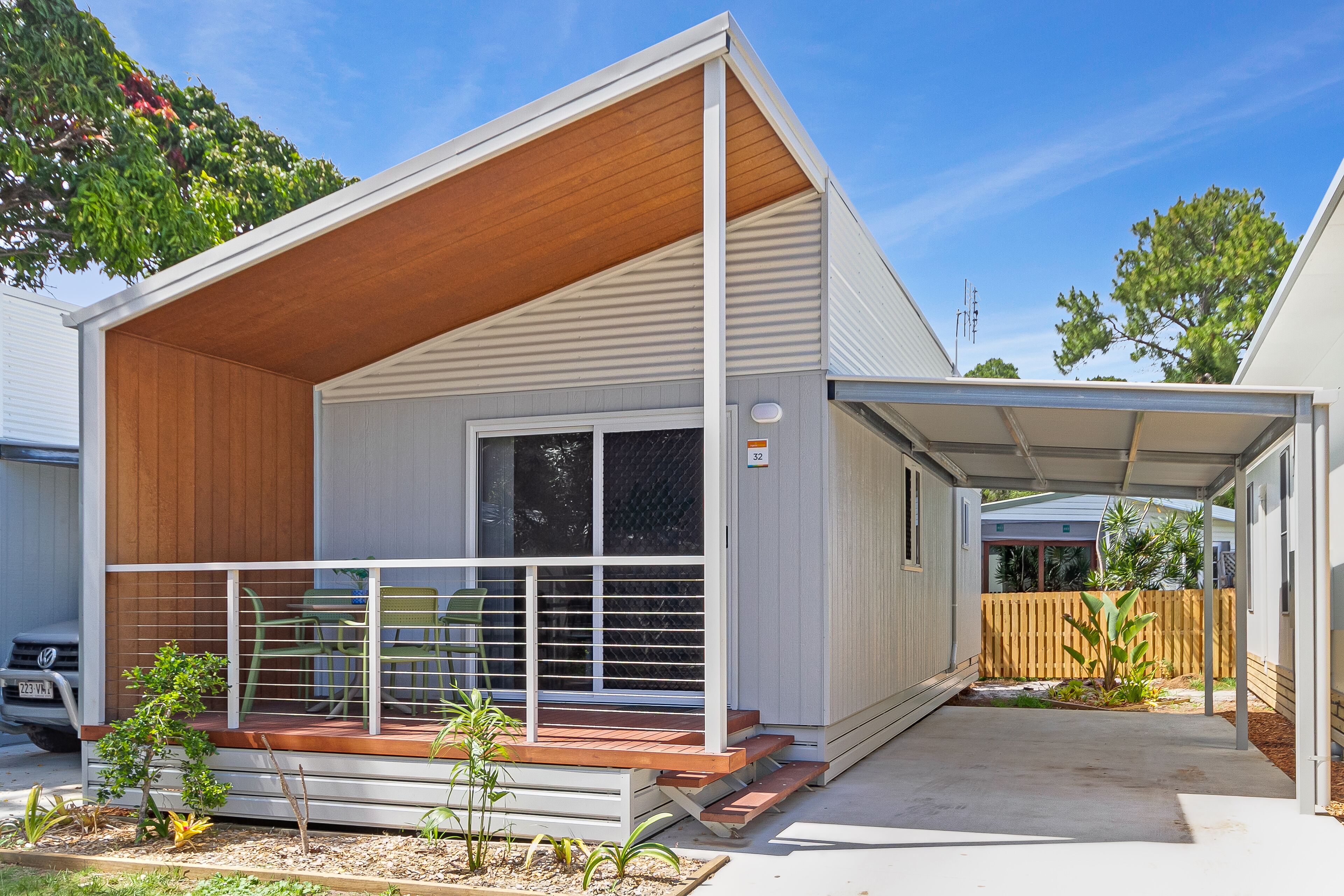 A single-story house with a covered porch, a small garden, and a wooden deck.