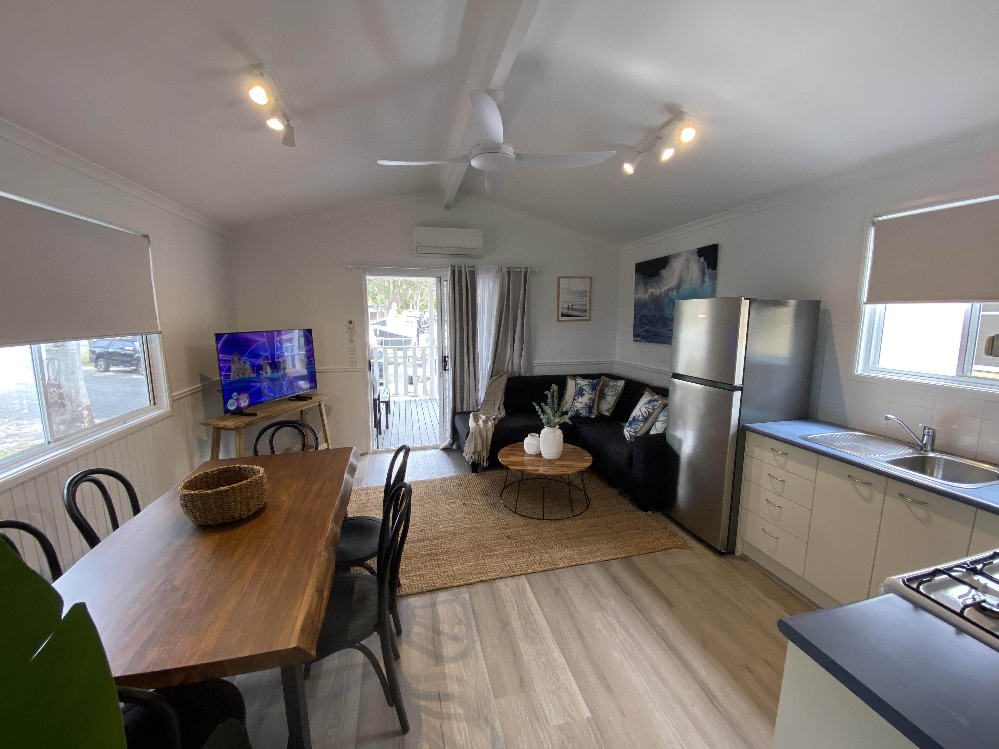 A compact kitchen with a dining area, a TV, and a refrigerator.