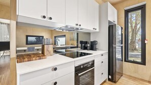 Una cocina moderna con armarios blancos, horno empotrado y refrigerador negro.
