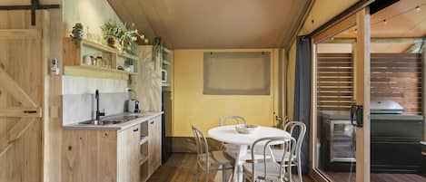 A compact kitchen with a dining area, wooden flooring, and a sliding glass door leading to an outdoor space.
