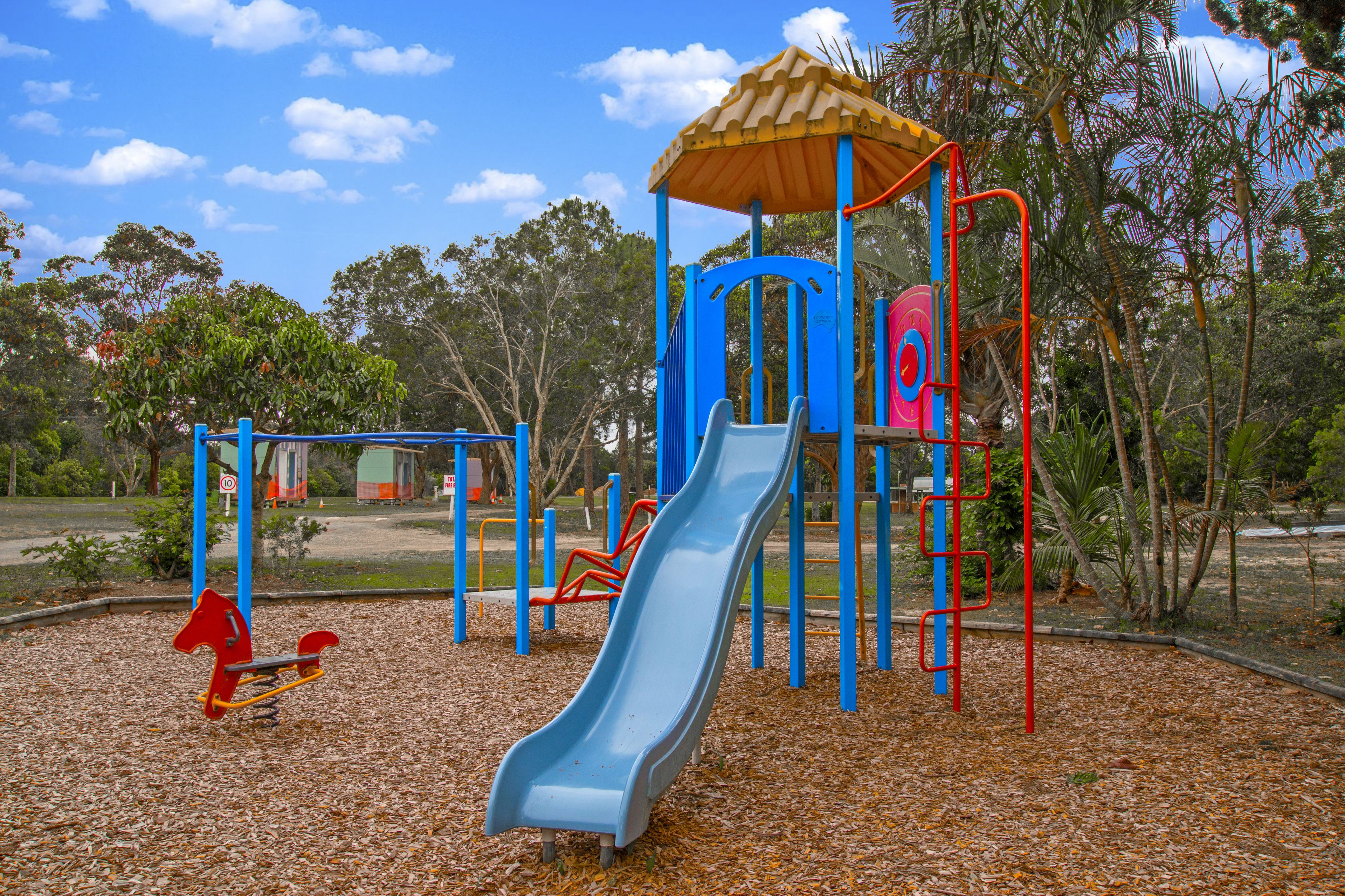 A playground with a slide, climbing structures, and a red horse-shaped swing set.