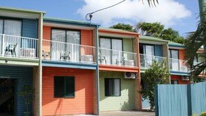 A row of colorful, two-story motel buildings with balconies and air conditioning units.