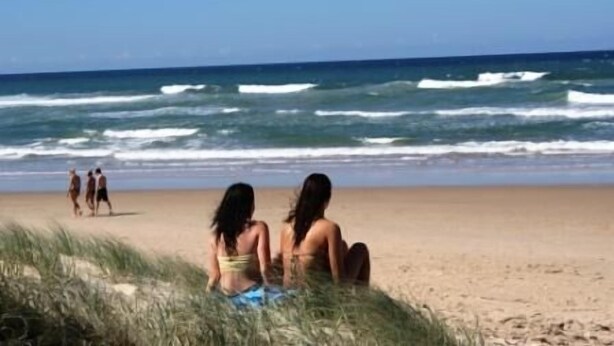 A beach with people sitting and walking.