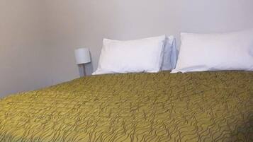 A bed with a patterned bedspread and two pillows.