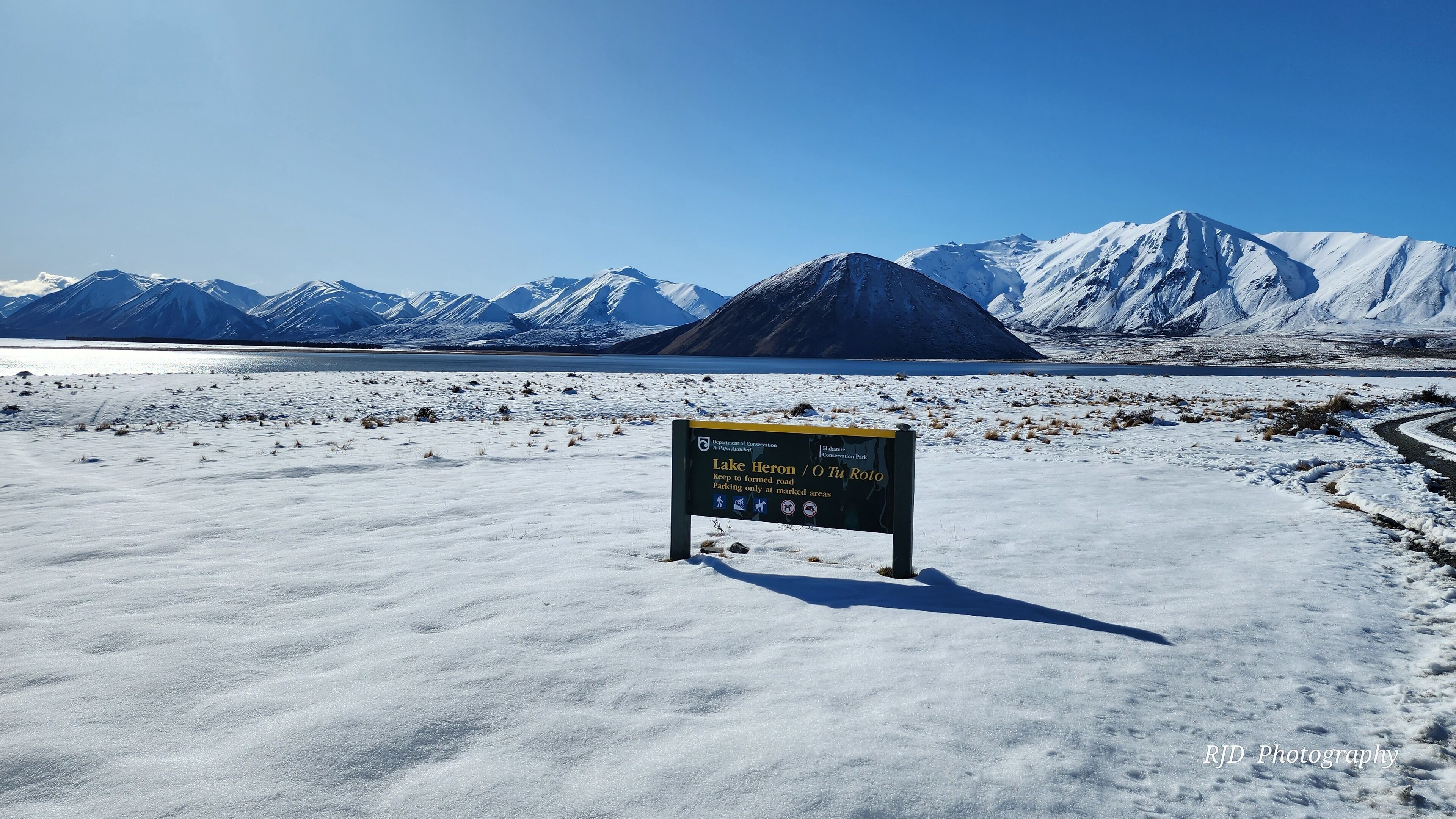A sign in a snowy landscape with a clear sky and mountains in the background.