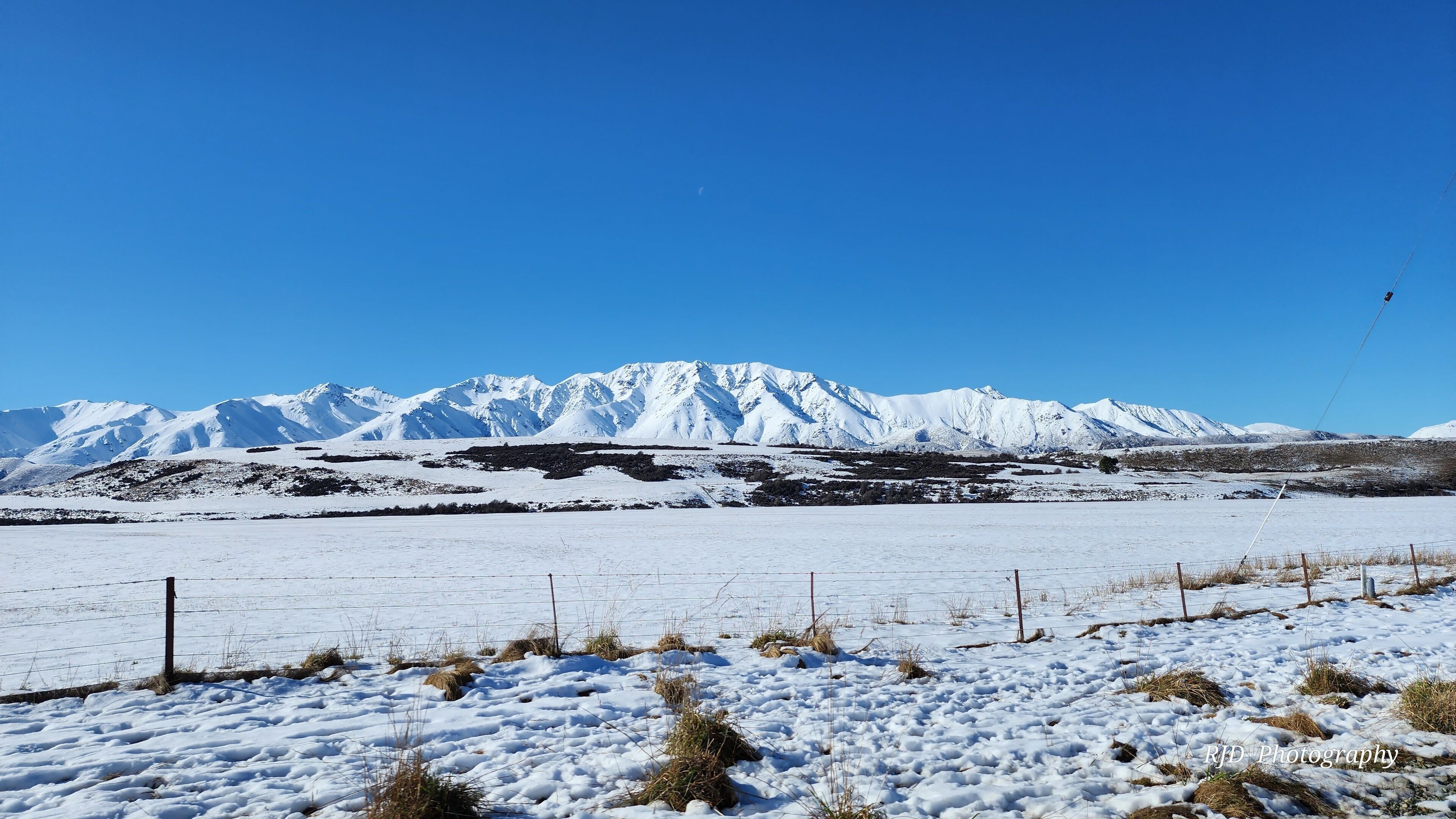 Un paisaje nevado con una cadena montañosa al fondo.