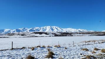 Un paisaje nevado con una cadena montañosa al fondo.