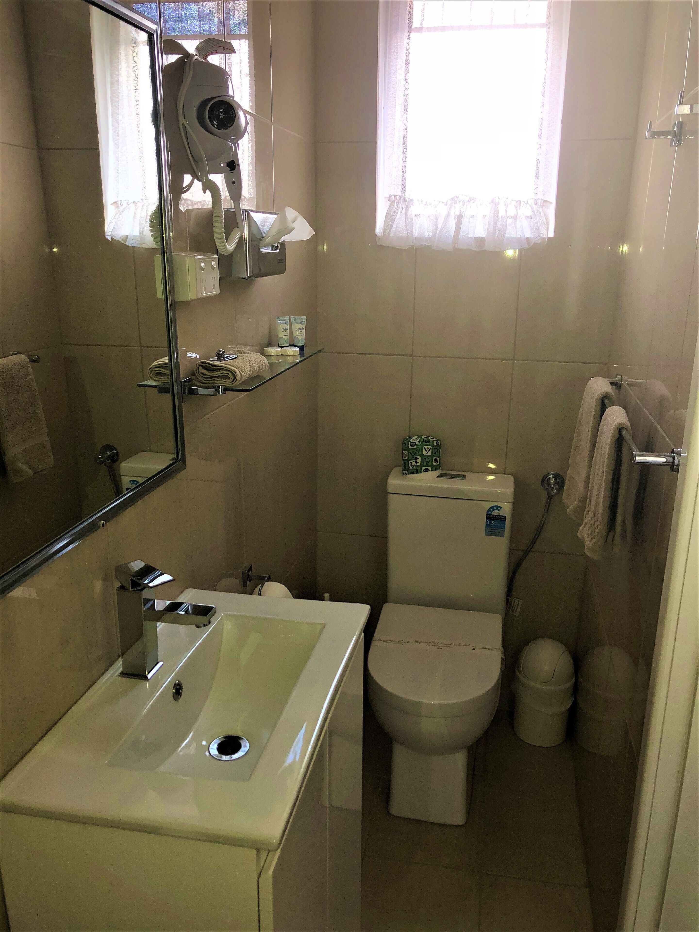 Un baño con lavamanos, inodoro y secador de pelo montado en la pared.