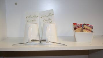 Una estantería blanca con dos tazas blancas etiquetadas “Clean Glass” y un cuenco con paquetes de galletas.